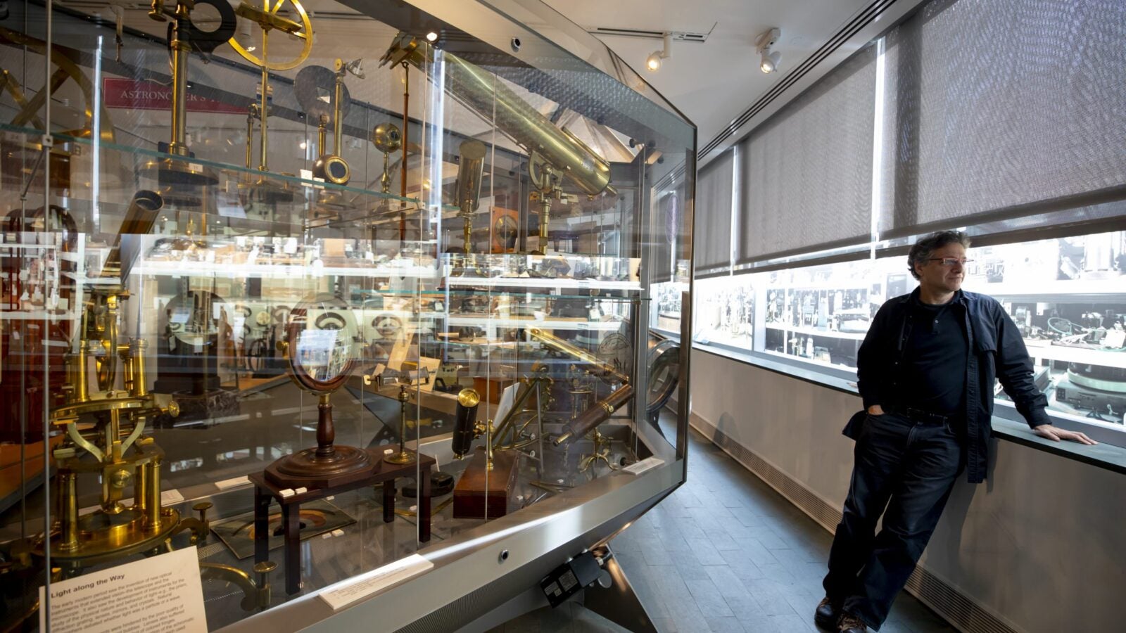 Peter Galison stands by cases of historical scientific instruments.