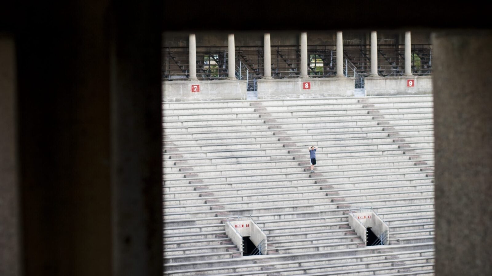 A runner stands on the steps of Harvard Stadium stairs.
