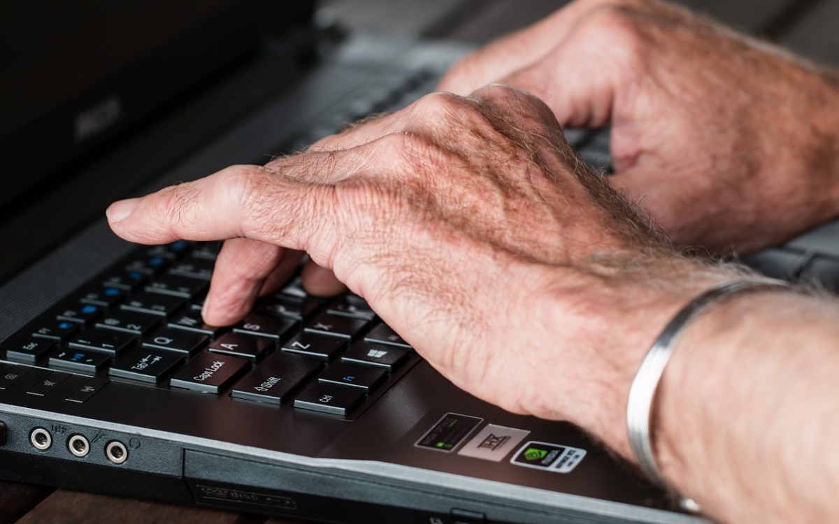 Arthritic hands typing on a keyboard.