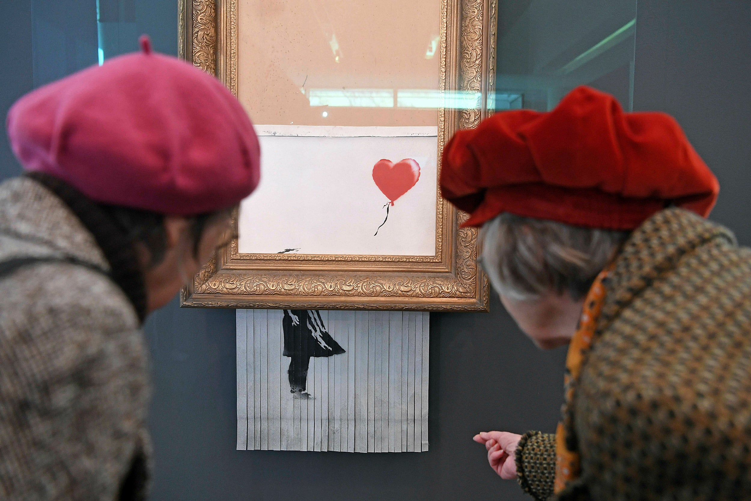 Two women wearing red berets inspect the shredded Banksy painting at the Museum Frieder Burda in Baden-Baden.