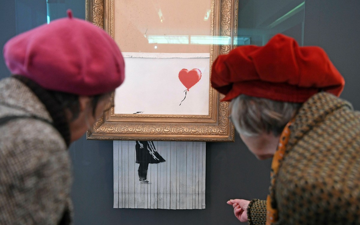 Two women wearing red berets inspect the shredded Banksy painting at the Museum Frieder Burda in Baden-Baden.