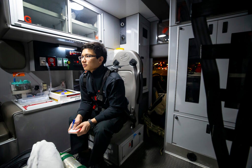Benjamin Ho takes notes in the back of an ambulance.