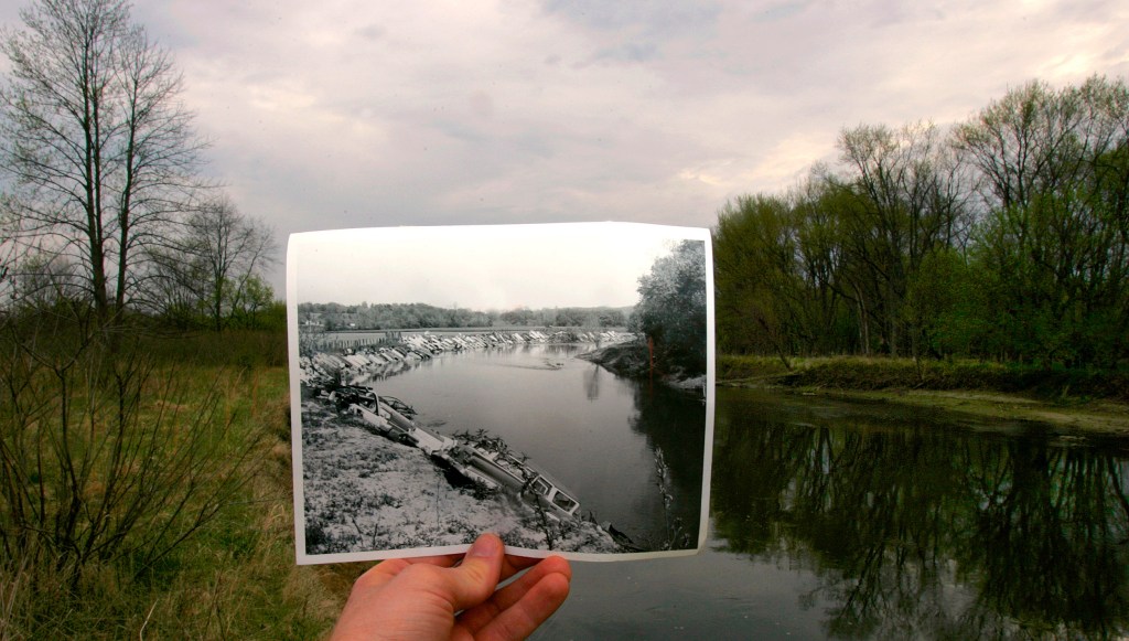 A 1967 photograph, showing old cars used as rip-rap along the banks of the Cuyahoga to protect it from erosion is held in front of the river decades later.