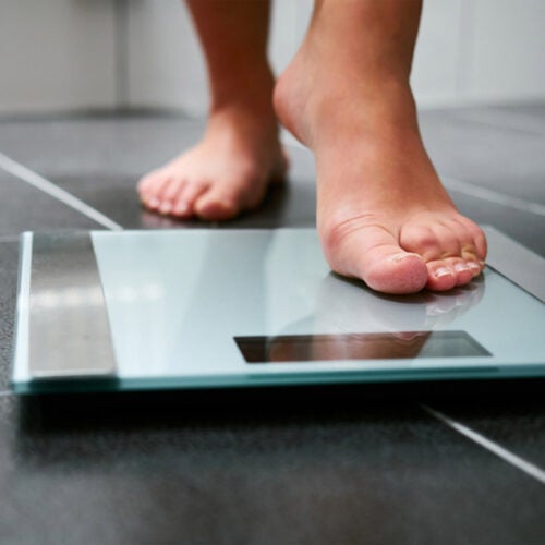 Person getting ready to weigh themselves on a scale.