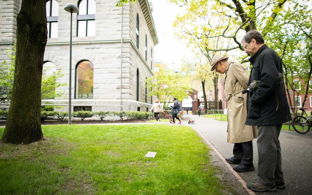 Two men examine plaque in Harvard Yard.