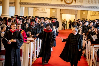 Larry Bacow and Jonathan Walton walk down the aisle of Memorial Church for the 2019 Baccalaureate Service.