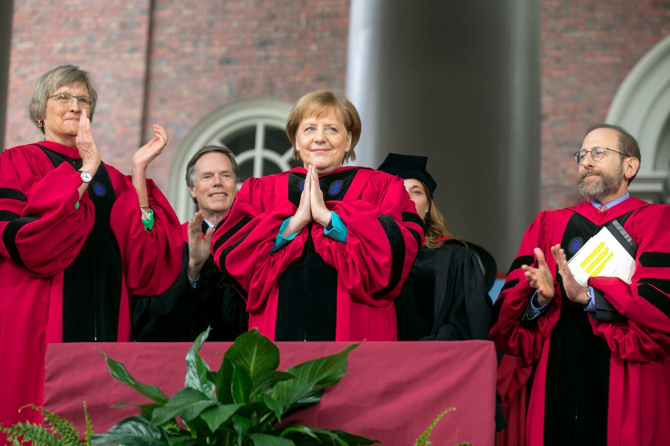 Angela Merkel holds her hands in a prayer acknowledging the applause after receiving her honorary degree.