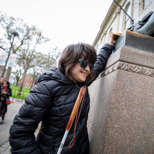 Jordan Scheffer touches the John Harvard statue.