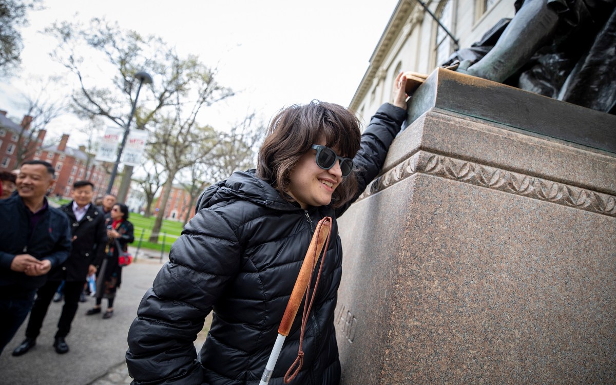 Jordan Scheffer touches the John Harvard statue.