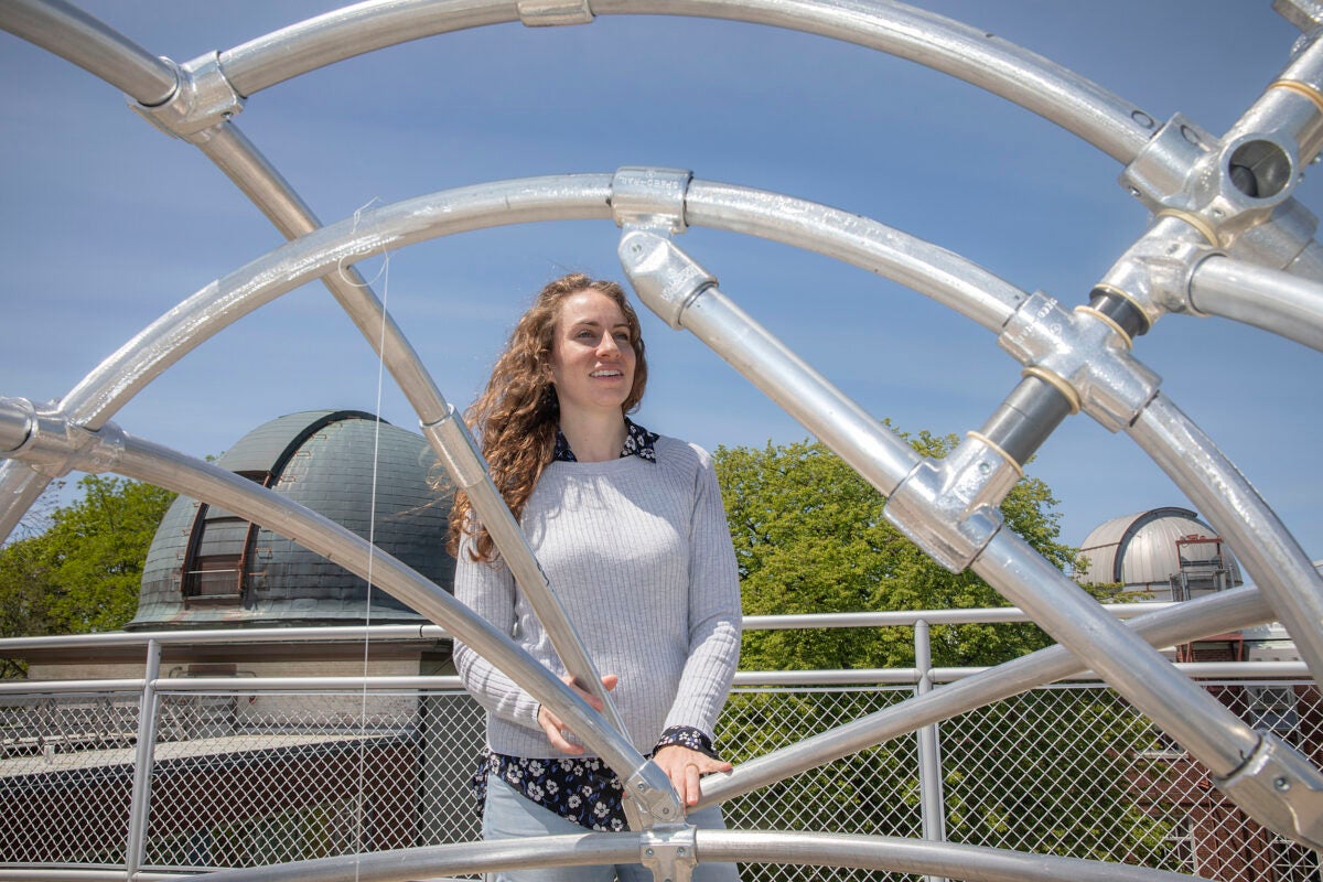 Center for Astrophysics astronomer Laura Kreidberg framed by a metal structure