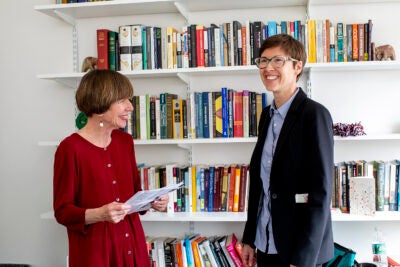 Kathleen Coleman (left) and Eleanor Finnegan chat in front of a bookcase