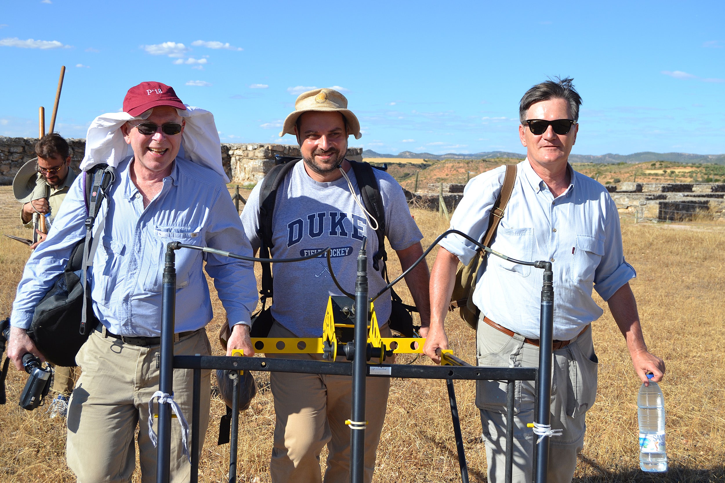 Three men holding excavating tool