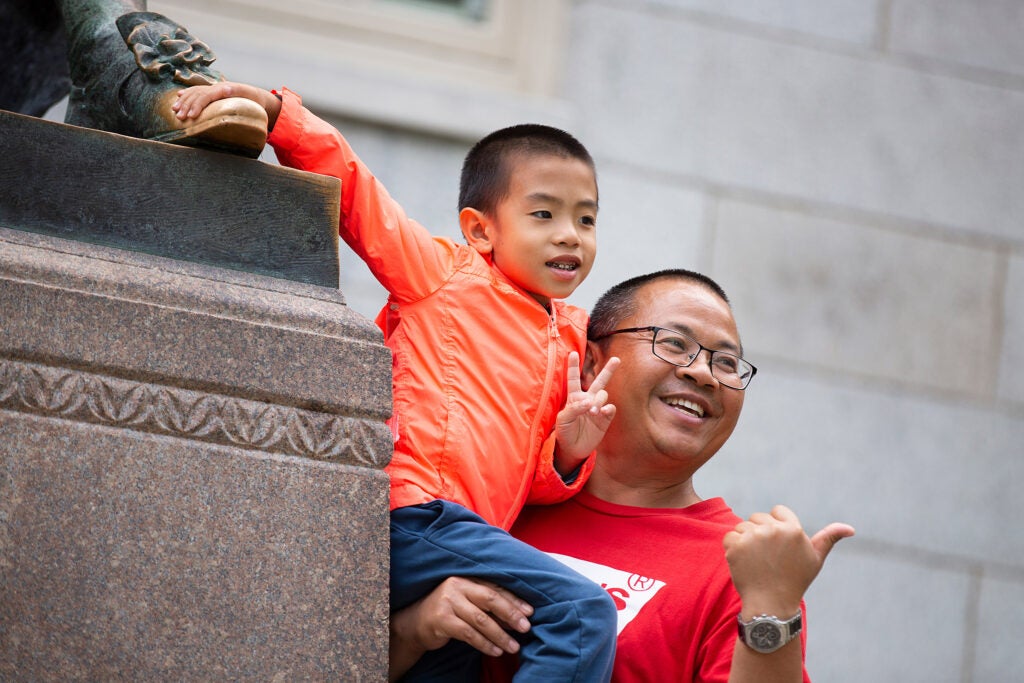 Father holds 6-year-old son who touches the statue's foot.