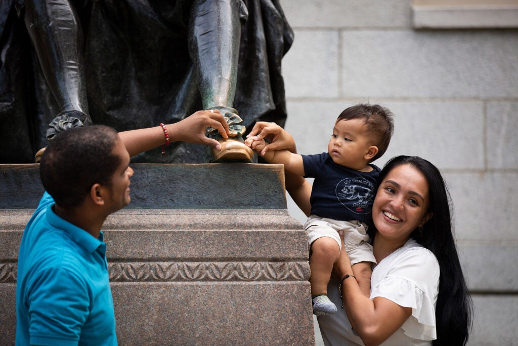 A couple with 9-month-old child pose at the foot of the sculpture.