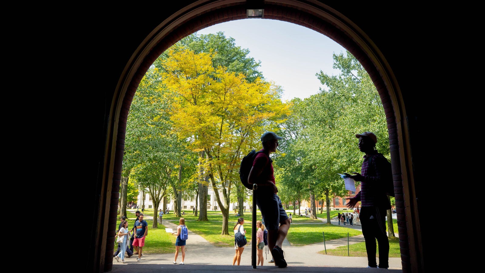 Two students stand under Sever Hall archway.