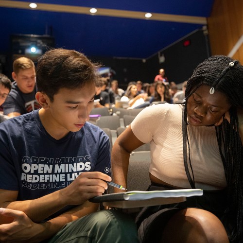 two students looking at notebook together
