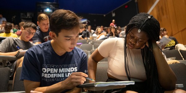 two students looking at notebook together