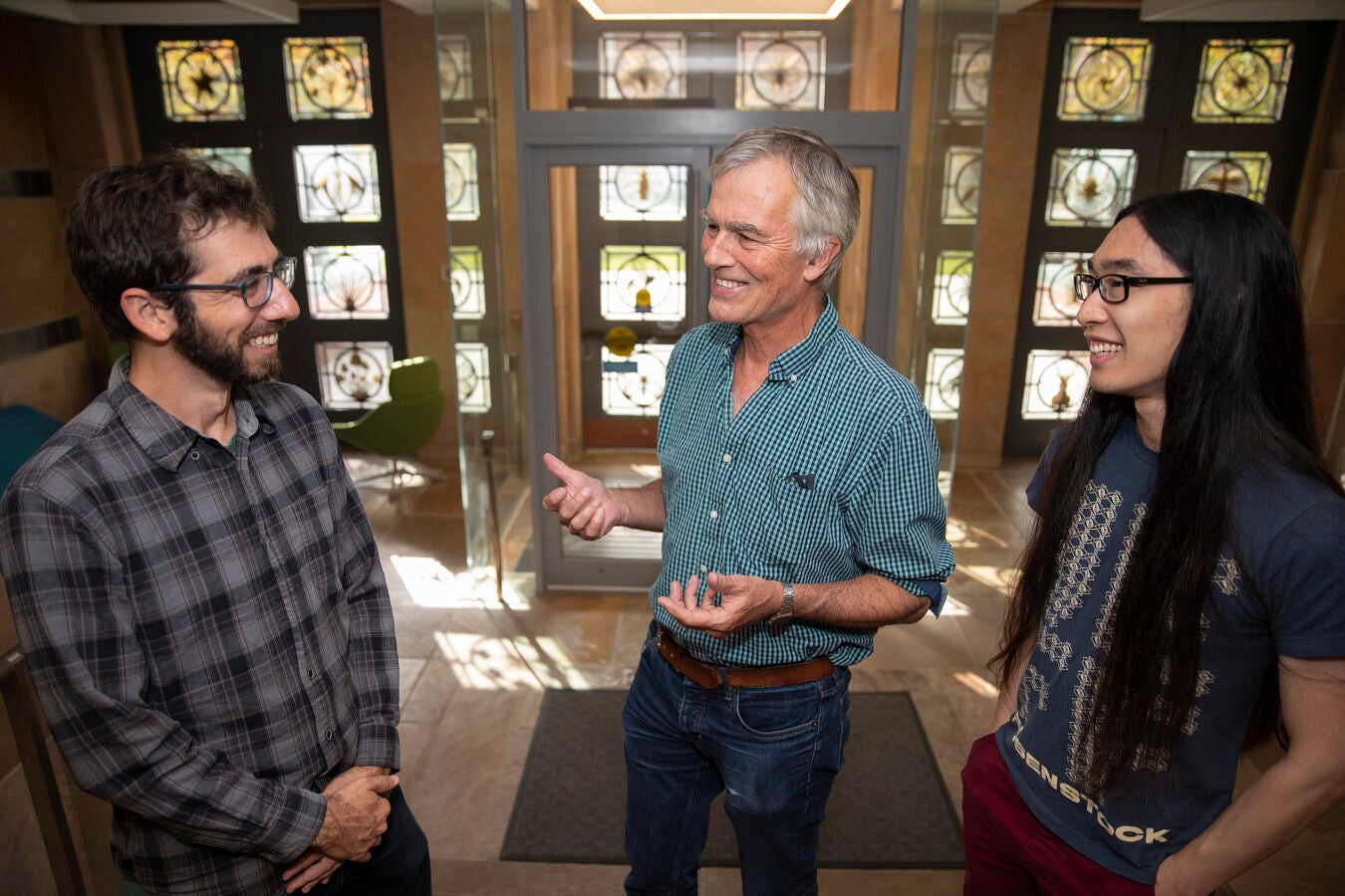 James Mallet (blue shirt) and colleagues Nate Edelman (plaid shirt) and Michael Miyagi (long hair) are the authors of a study that butterfly genomes inside the biology labs.