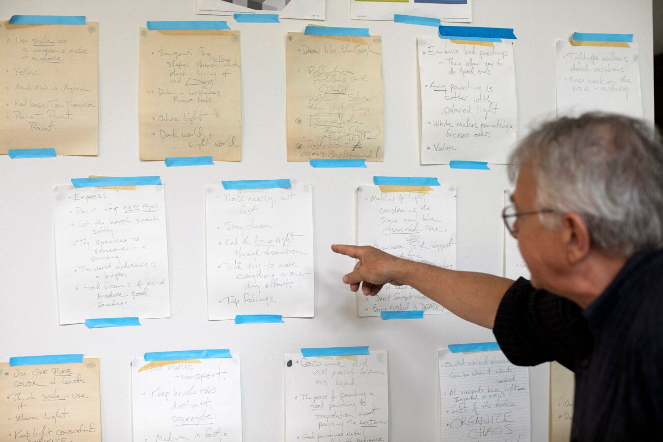 Stephen Coit points to an array of helpful and inspiration notes taped to his studio wall.