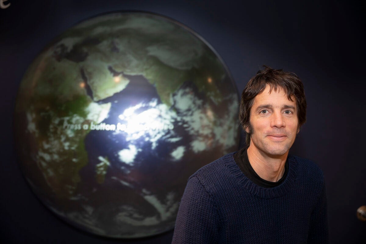 A portrait-style photo of professor in front of a large globe