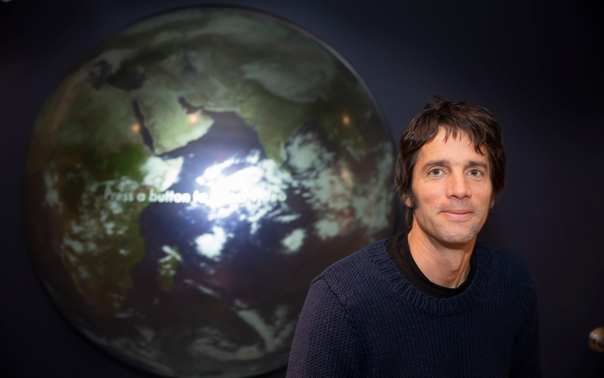 A portrait-style photo of professor in front of a large globe