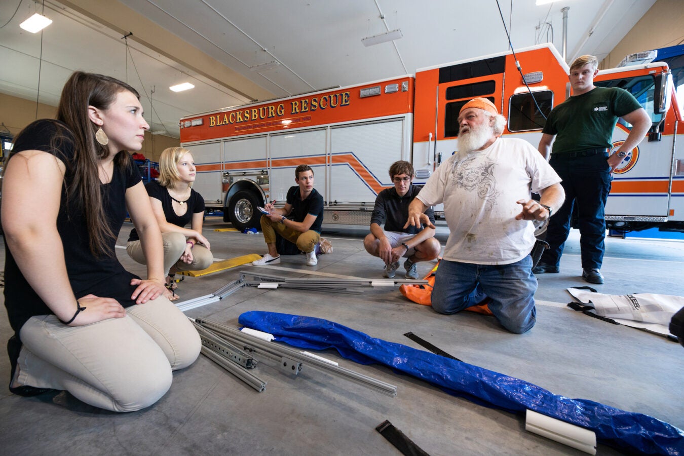 Andy and the engineering team kneeling down, showing an EMT the prototype