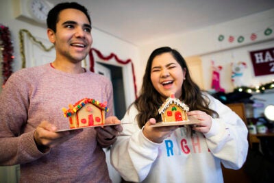 Two students holding gingerbread houses.