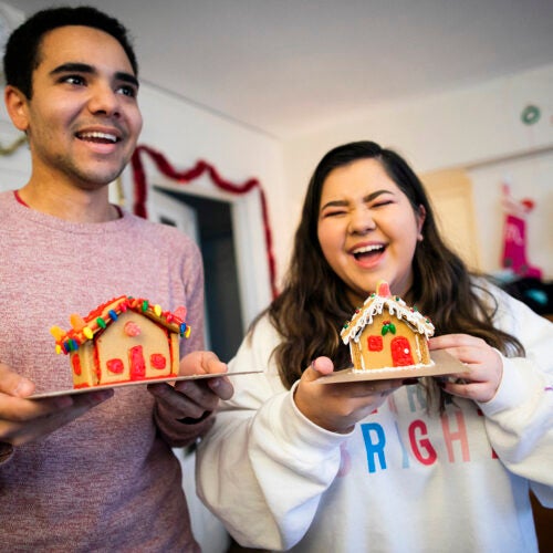 Two students holding gingerbread houses.