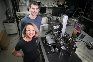 Two researchers in a lab with a large microscope.