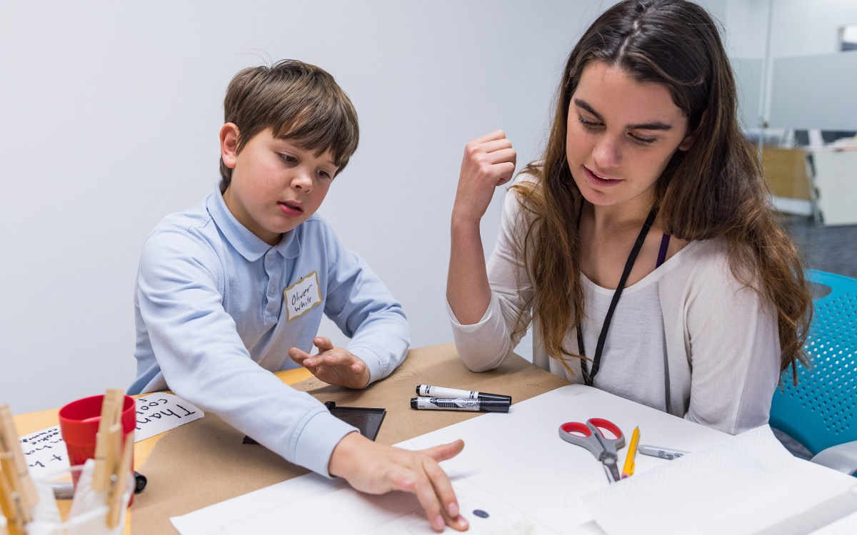 Fifth-grader putting fingerprints on a page with mentor.