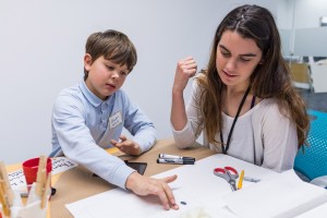 Fifth-grader putting fingerprints on a page with mentor.