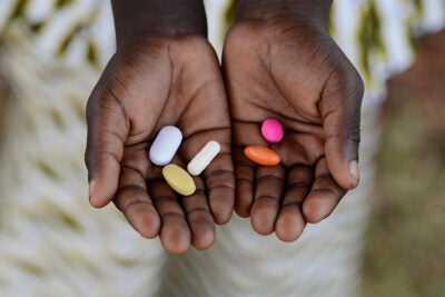 Black African boy holding antibiotic pills.