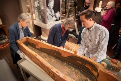 Dennis Piechota (left), Jane Drake, and Adam Aja view the inside of the coffin of Ankh-khonsu.