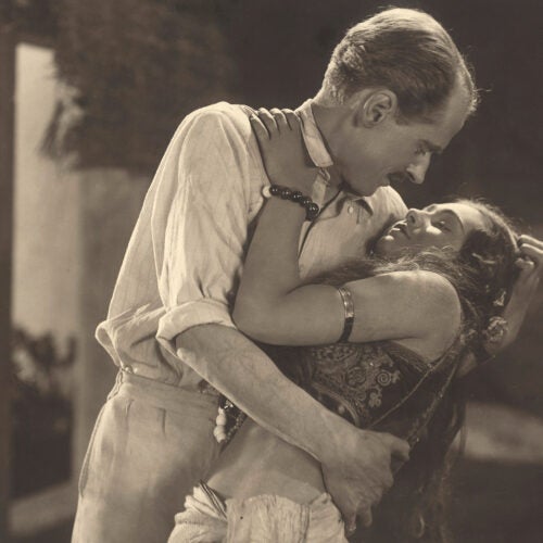 Man embracing woman in still from "The Pleasure Garden."