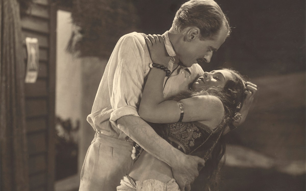 Man embracing woman in still from "The Pleasure Garden."