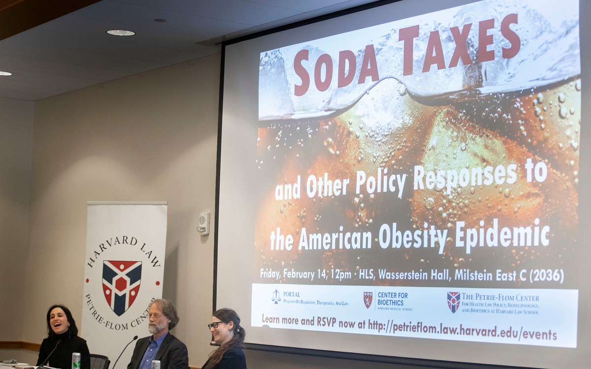 Three people sitting in front of a screen with Soda Taxes on it.