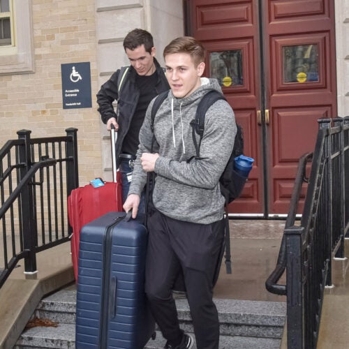 Two students with suitcases.