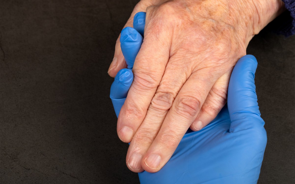 Caregiver holding elderly patients hand at home.