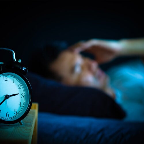 Man in bed suffering insomnia.