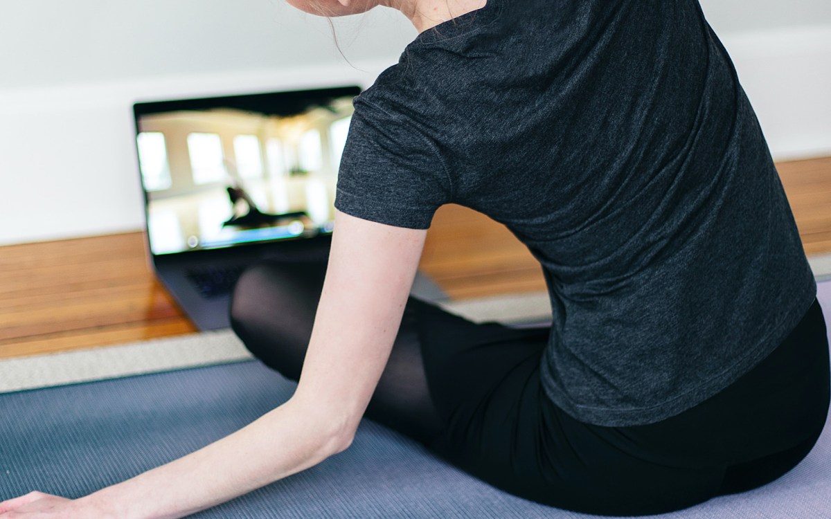 Woman doing yoga in front of laptop.