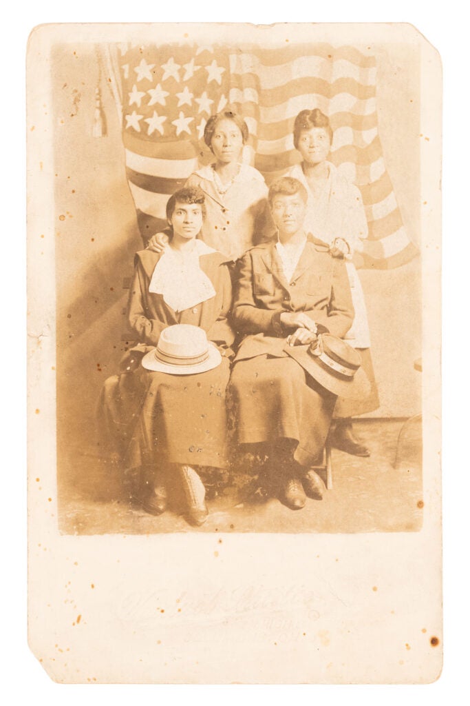 Suffrage postcard of four African American women in front of a U.S. flag.