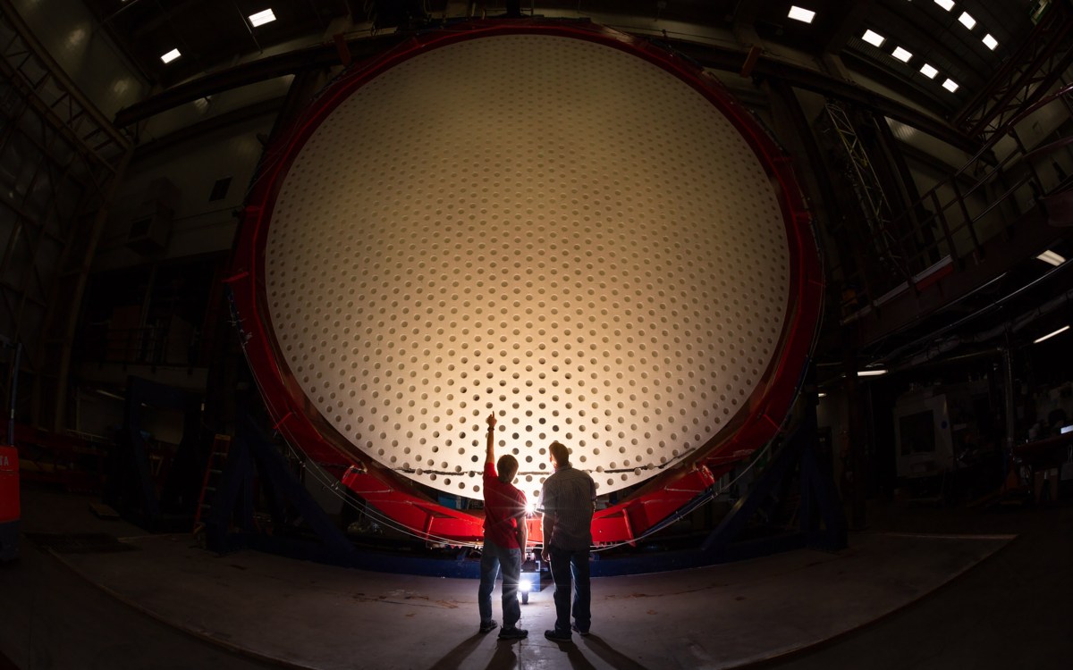 Two individuals stand in front of Magellan Mirror.