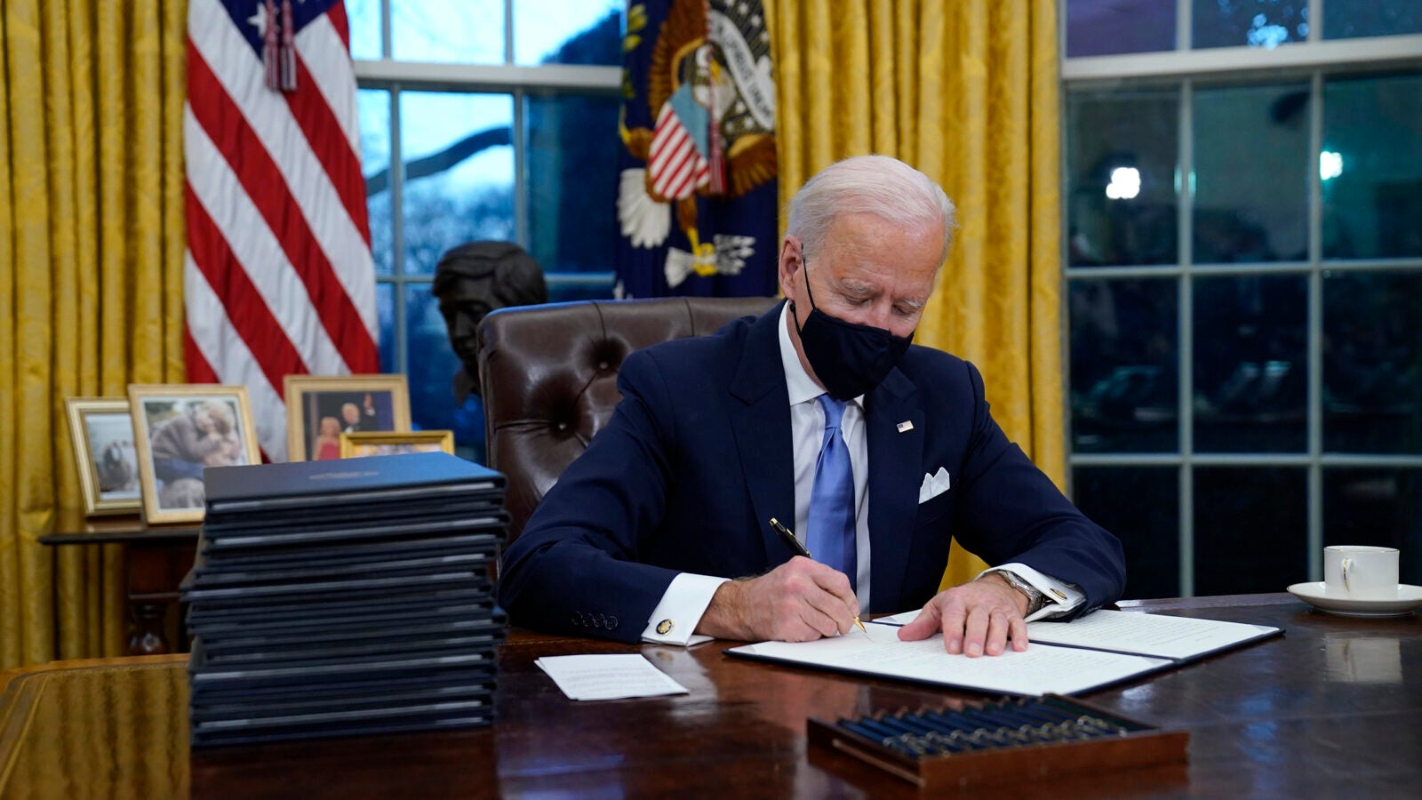 Joe Biden signs his first executive orders in the Oval Office.