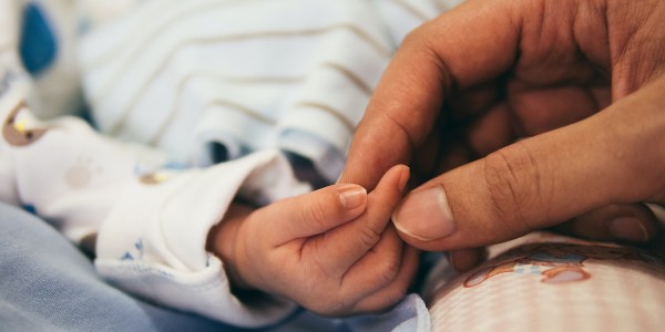 Baby and adult holding hands.