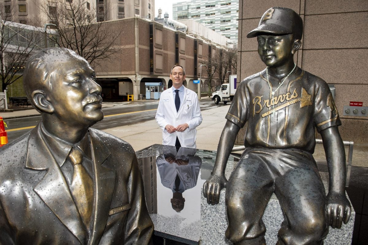 Patrick Ott, Associate Prof of Medicine at HMS and DFCI, stands by the statues of Dana-Farber founder Sidney Farber.