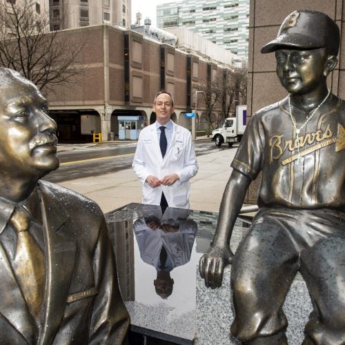 Patrick Ott, Associate Prof of Medicine at HMS and DFCI, stands by the statues of Dana-Farber founder Sidney Farber.