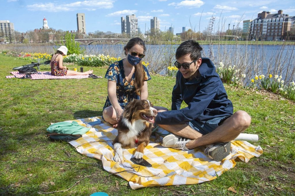 Karen Mata and Rodrigo Guerra relax along the Charles River with their dog.
