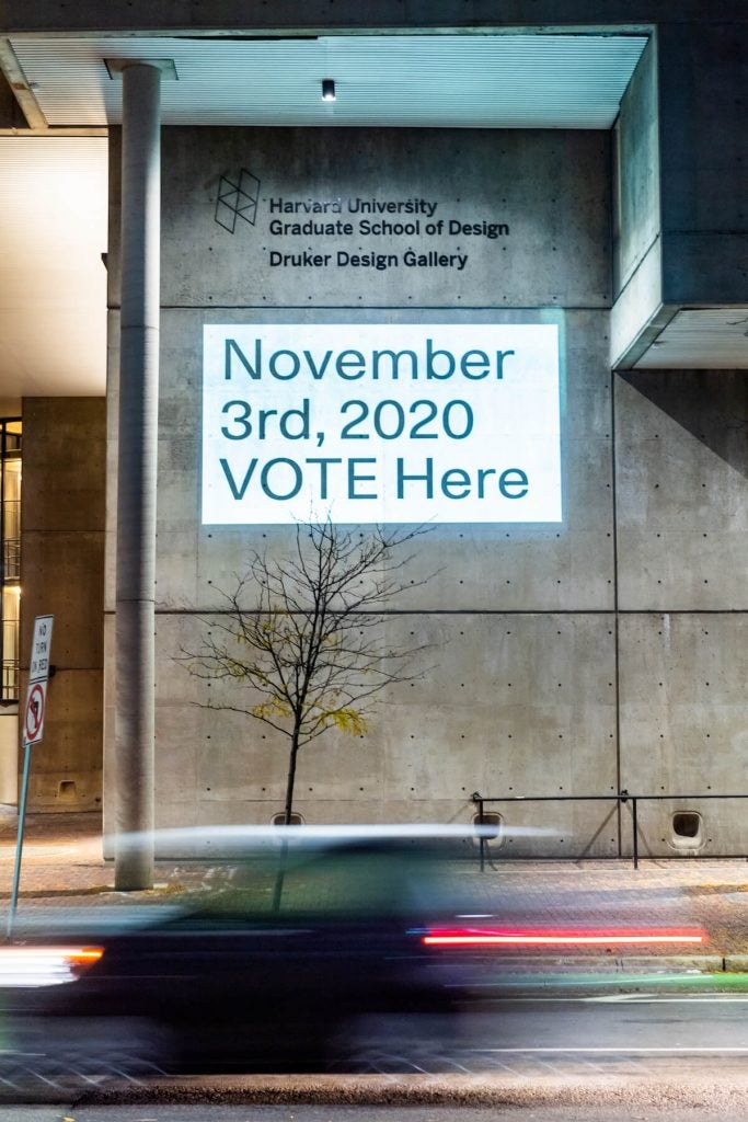 A projection on a building saying where people can vote.
