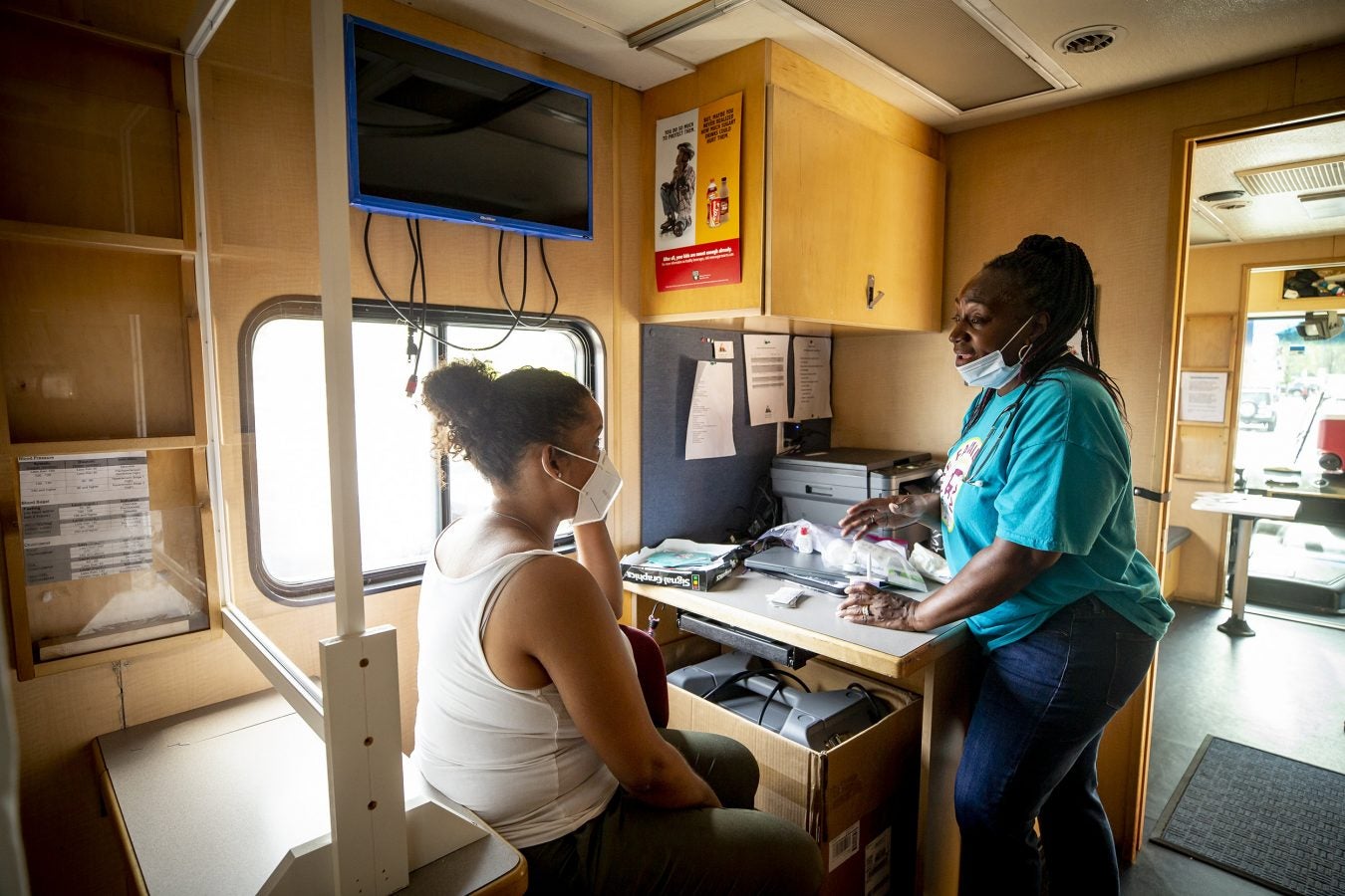 Rainelle Walker White, right, assistant director, while eating her lunch, chats with staffer Joanne Suarez inside Harvard University's Family Van.