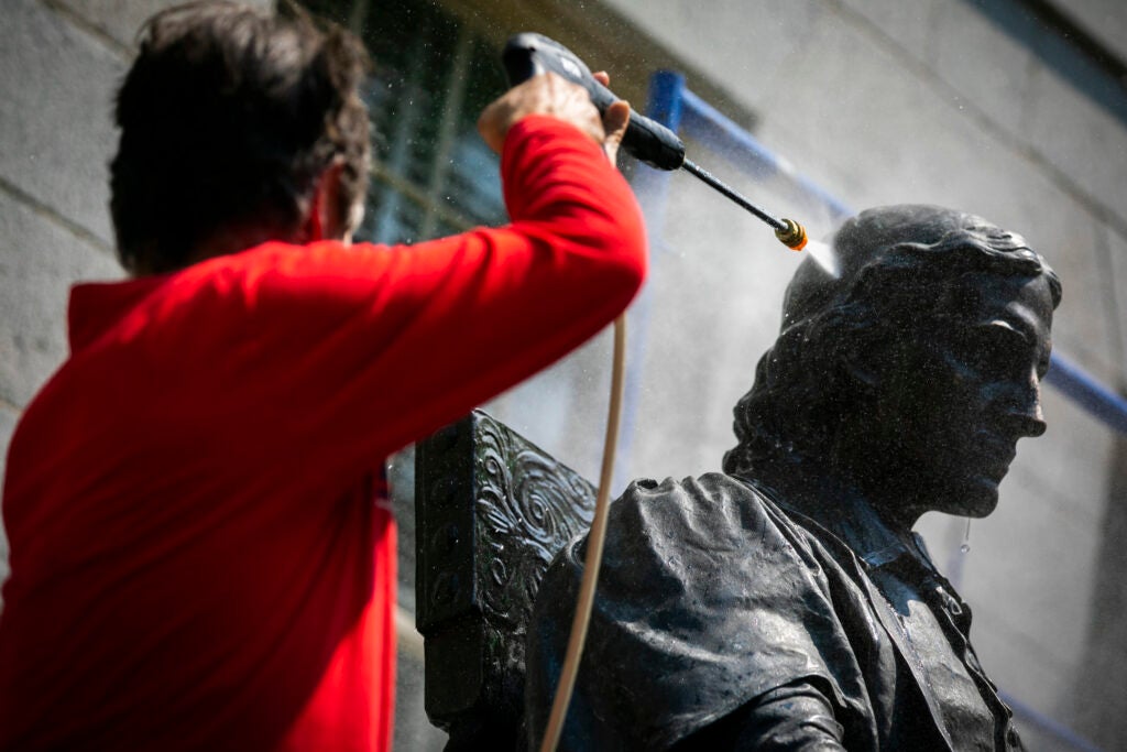John Harvard statue being cleaned.
